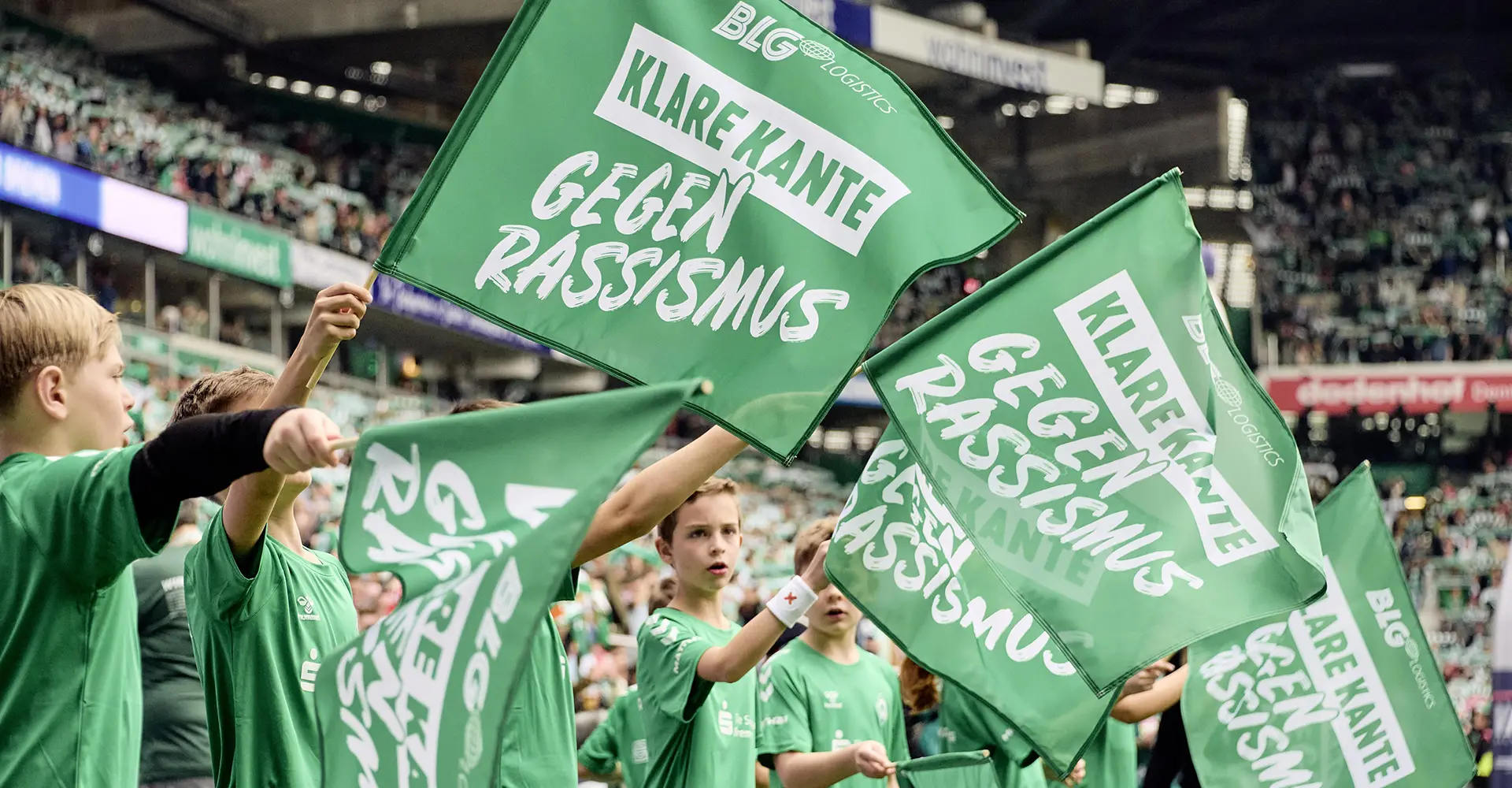 Children waving flags against racism in a stadium (Photo)