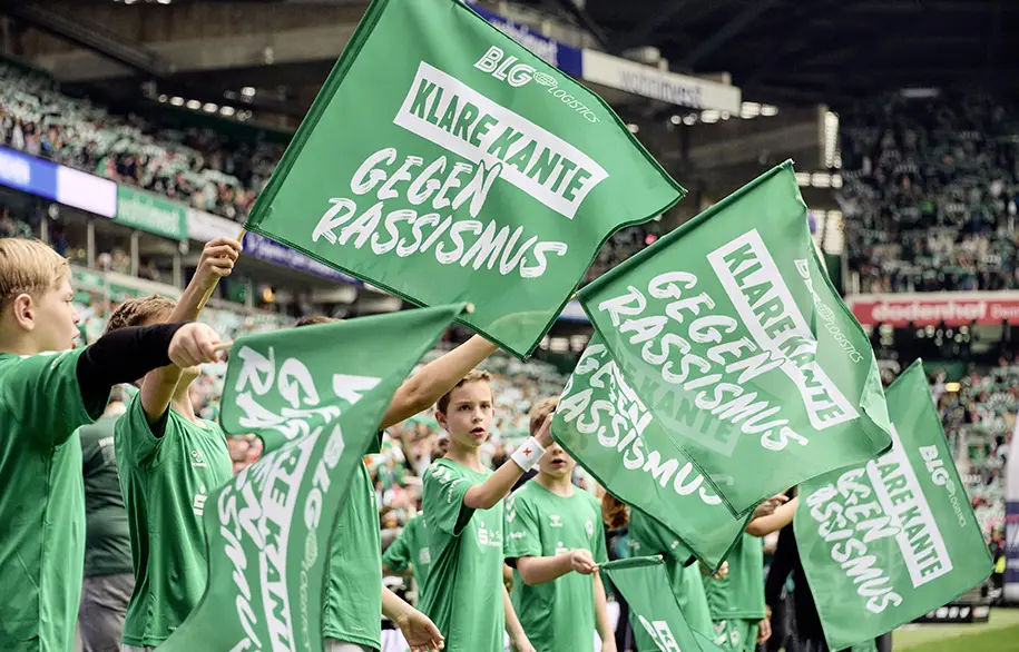 Children waving flags against racism in a stadium (Photo)