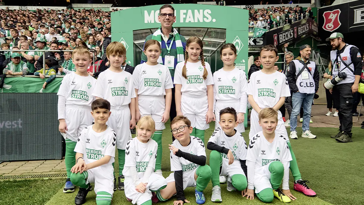 Matthias Magnor, CEO of the BLG with children wearing Weder Strom merchandise at a stadium (Photo)