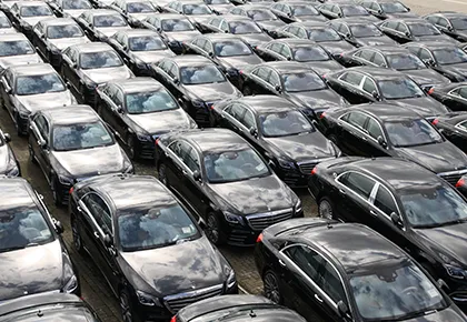 Luftaufnahme mehrerer langer, dicht aneinander geparkter Reihen schwarzer Autos