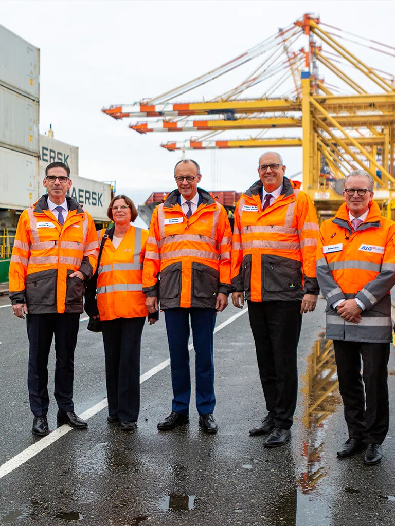 Vorstände und Friedrich Merz am Hafen in orangen Westen (Foto)