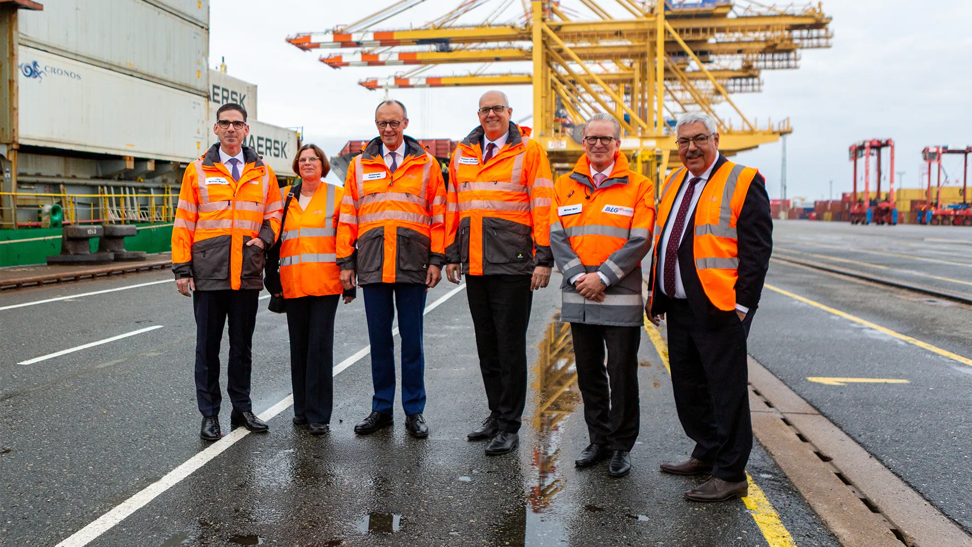 Vorstände und Friedrich Merz am Hafen in orangen Westen (Foto)