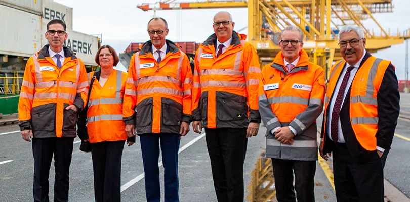 Vorstände und Friedrich Merz am Hafen in orangen Westen (Foto)