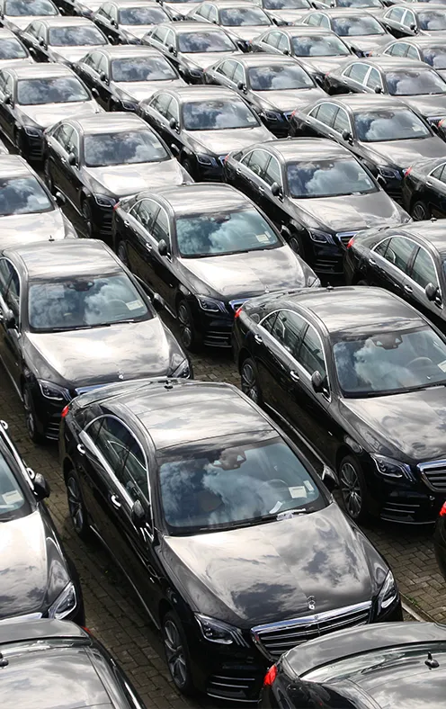 Aerial view of multiple long rows of closely parked black cars 