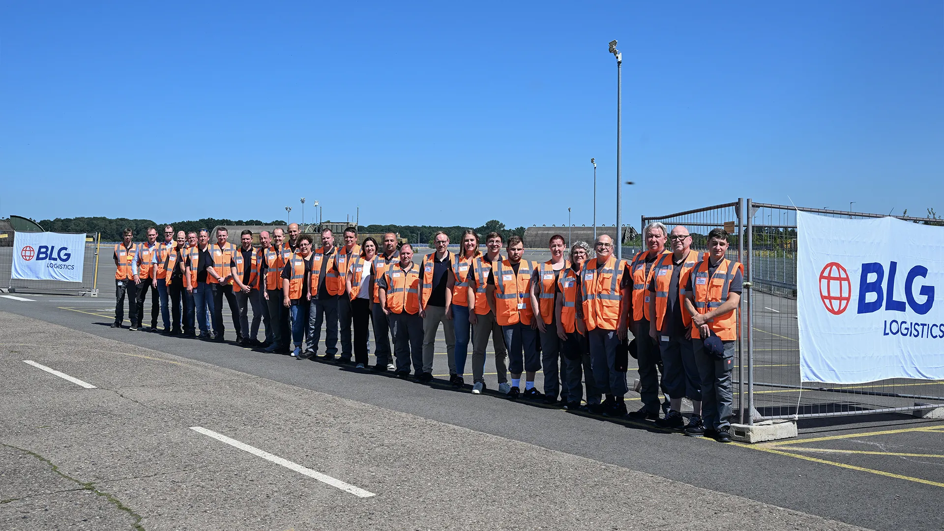 Group photo of employees outdoors wearing orange vests (Photo)