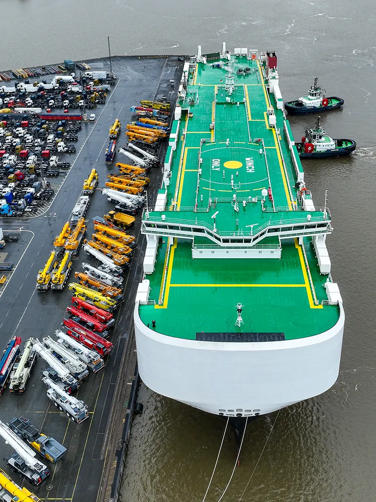 Aerial shot of a boat with docking station at the harbor and many vehicles parked next to it (Photo)