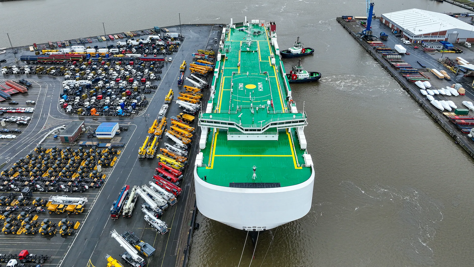 Aerial shot of a boat with docking station at the harbor and many vehicles parked next to it (Photo)